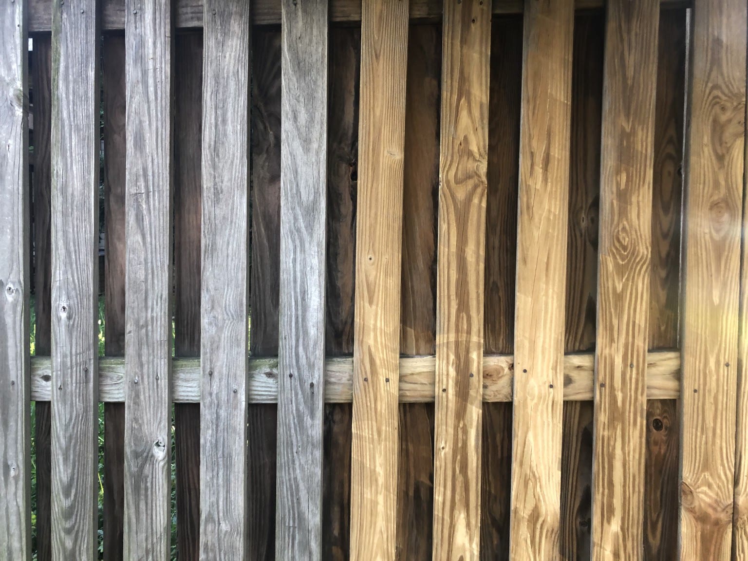Wood fence with the weathered side beside the freshly pressure-washed side